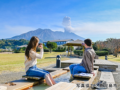 桜島を眺める男女の写真