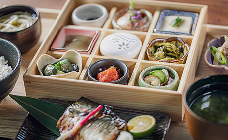 9つに仕切られた木箱に9つの料理が盛られ、さらに魚やお吸い物などたくさんの料理がある福岡店舗限定のオリジナルメニューここの香の写真