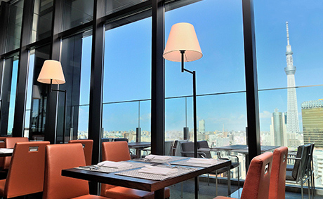 レストラン＆バー。4人掛けのテーブル席と大きな窓ガラスの外には東京スカイツリーが見える写真