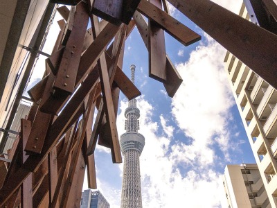 ホテルエントランス（昼）｜木組みのアーチ越しに仰ぎ見る、青空にそびえ立つ東京スカイツリー®。