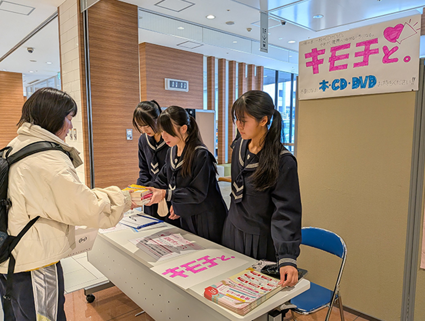 来場者から支援品を受け取る高校生 